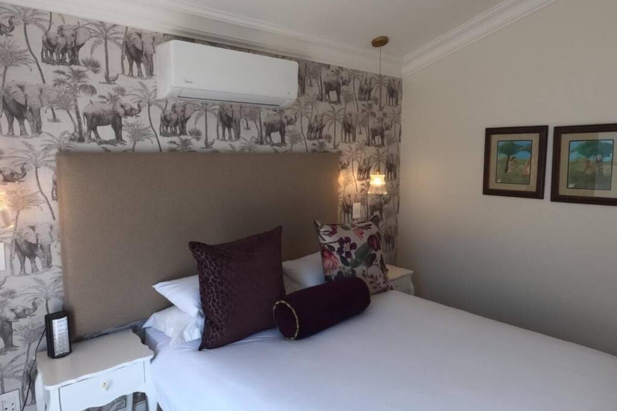 Una habitación de hotel con cama, mesita de noche y aire acondicionado instalado en la pared.