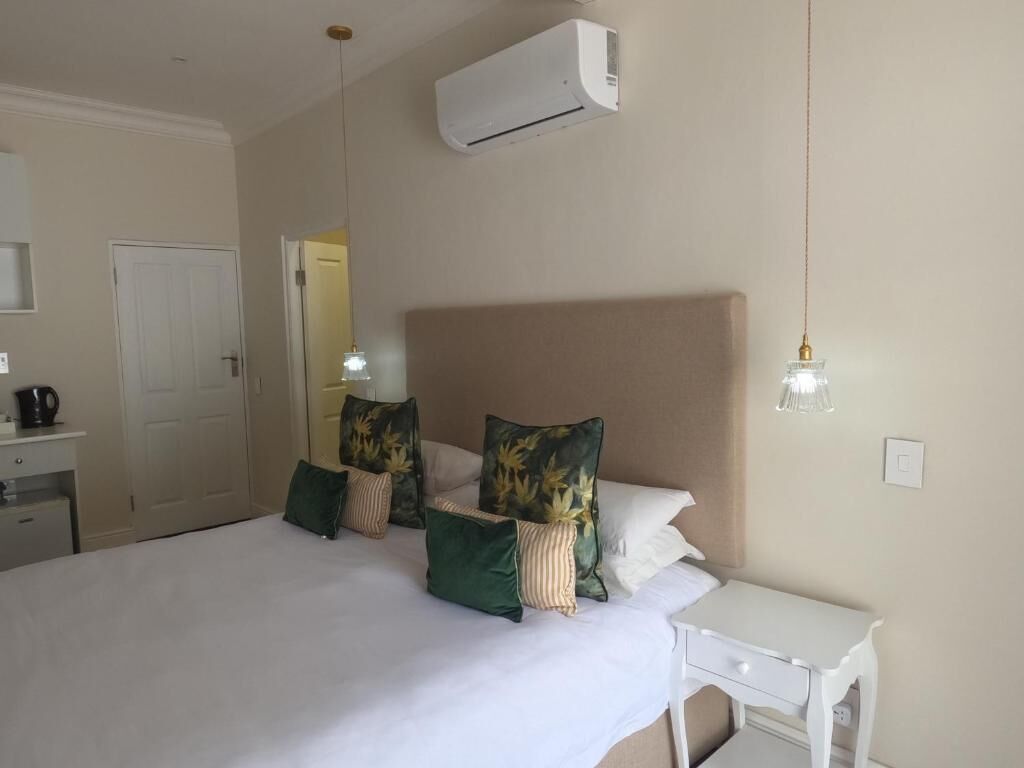 A hotel room with a bed, bedside table, and an air conditioning unit.