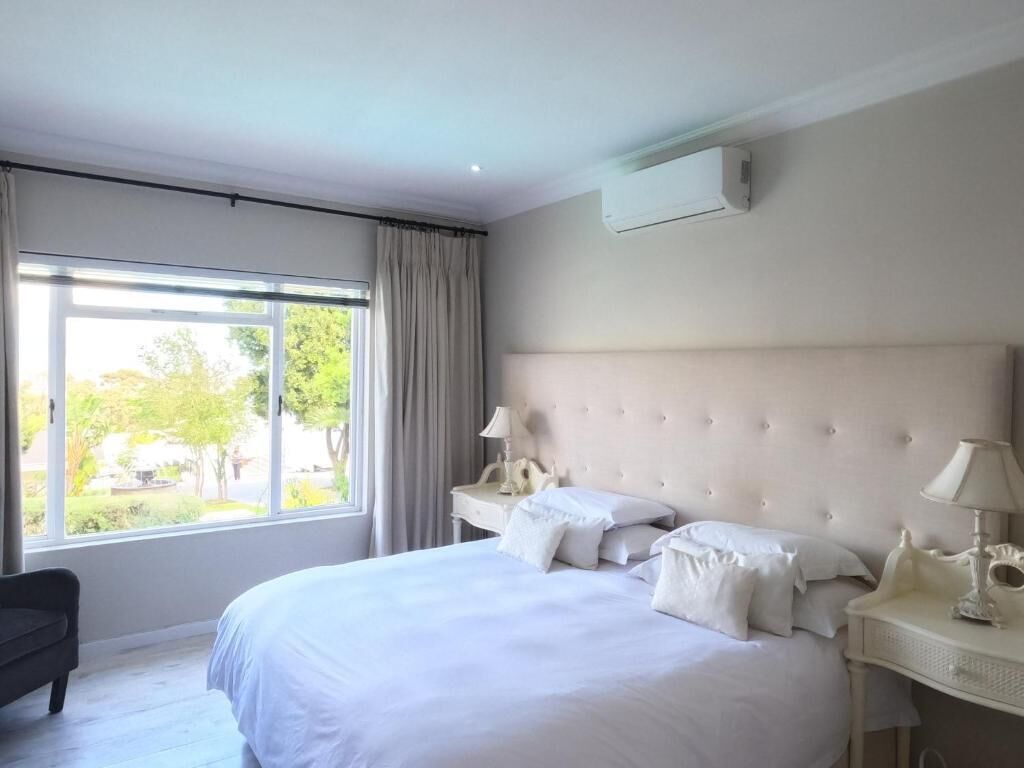 A hotel room with a large bed, a bedside table, a lamp, and a window with curtains.