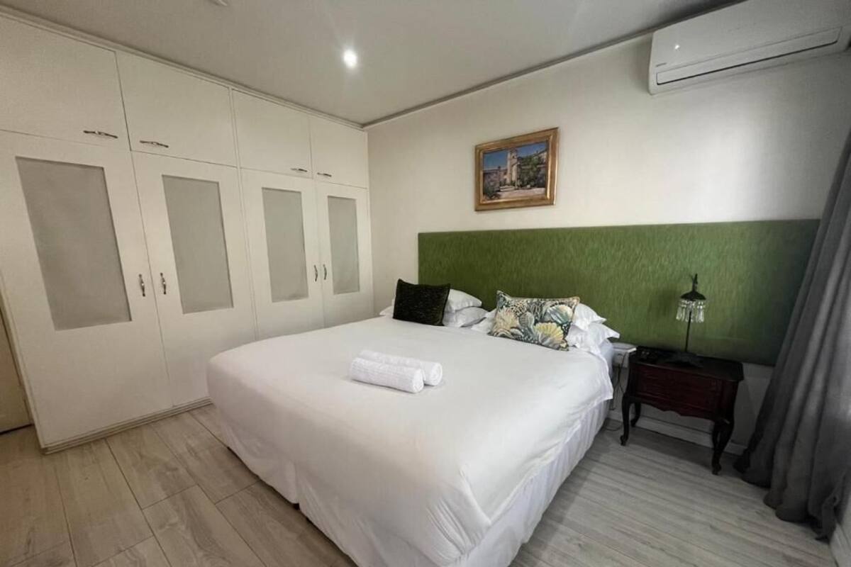 Un dormitorio con cama, armario, mesita de noche y un cuadro en la pared.