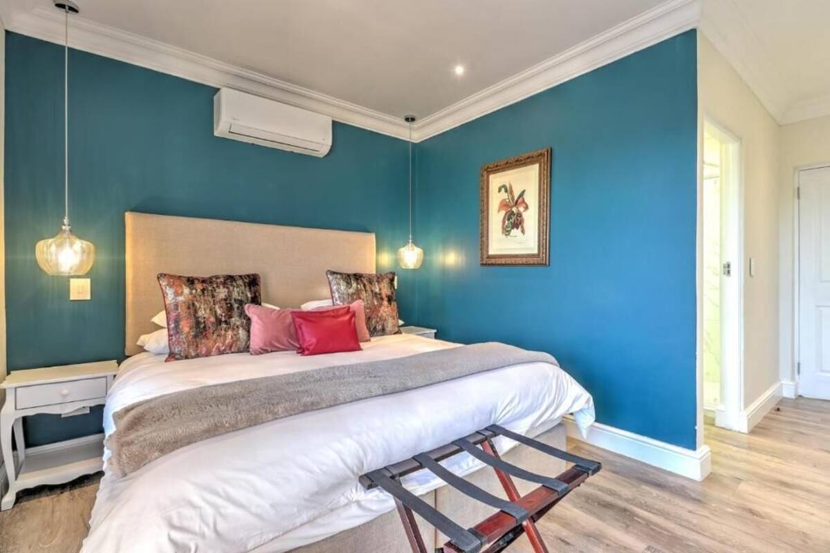 Un dormitorio con una cama, mesitas de noche, una lámpara colgante y un cuadro en la pared.