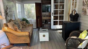 A covered porch with wicker furniture, a ceiling fan, and a television. - Historic Cigar Barons Mansion (Key West)