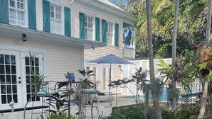 A patio with two chairs, a small table, and a decorative umbrella. - Historic Cigar Barons Mansion (Key West)