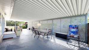 An outdoor patio with a table and chairs, a grill, and a basketball hoop. - Cookies Hideway - Coastal holiday vibes. (WOOLI)