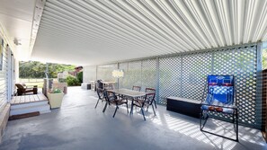 Eine Terrasse im Freien mit Tisch, Stühlen, einem Grill und einem Basketballkorb.