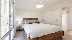 Une chambre à coucher avec un lit en bois, une lampe de chevet et une vue sur l’extérieur par une fenêtre.
