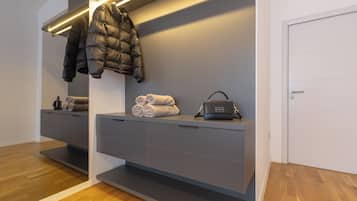 A modern bathroom with a grey vanity, a towel rack, a puffer jacket, and a handbag.
