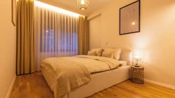 Une chambre à coucher avec un lit, des rideaux, un luminaire fixé au mur et une petite table de chevet avec une lampe.