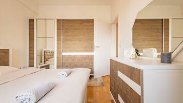 A modern bedroom with a large bed, a dresser, a mirror, and a view of the outside.