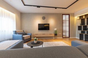 Una sala de estar moderna con un sofá, una mesa de centro, un televisor y una estantería.