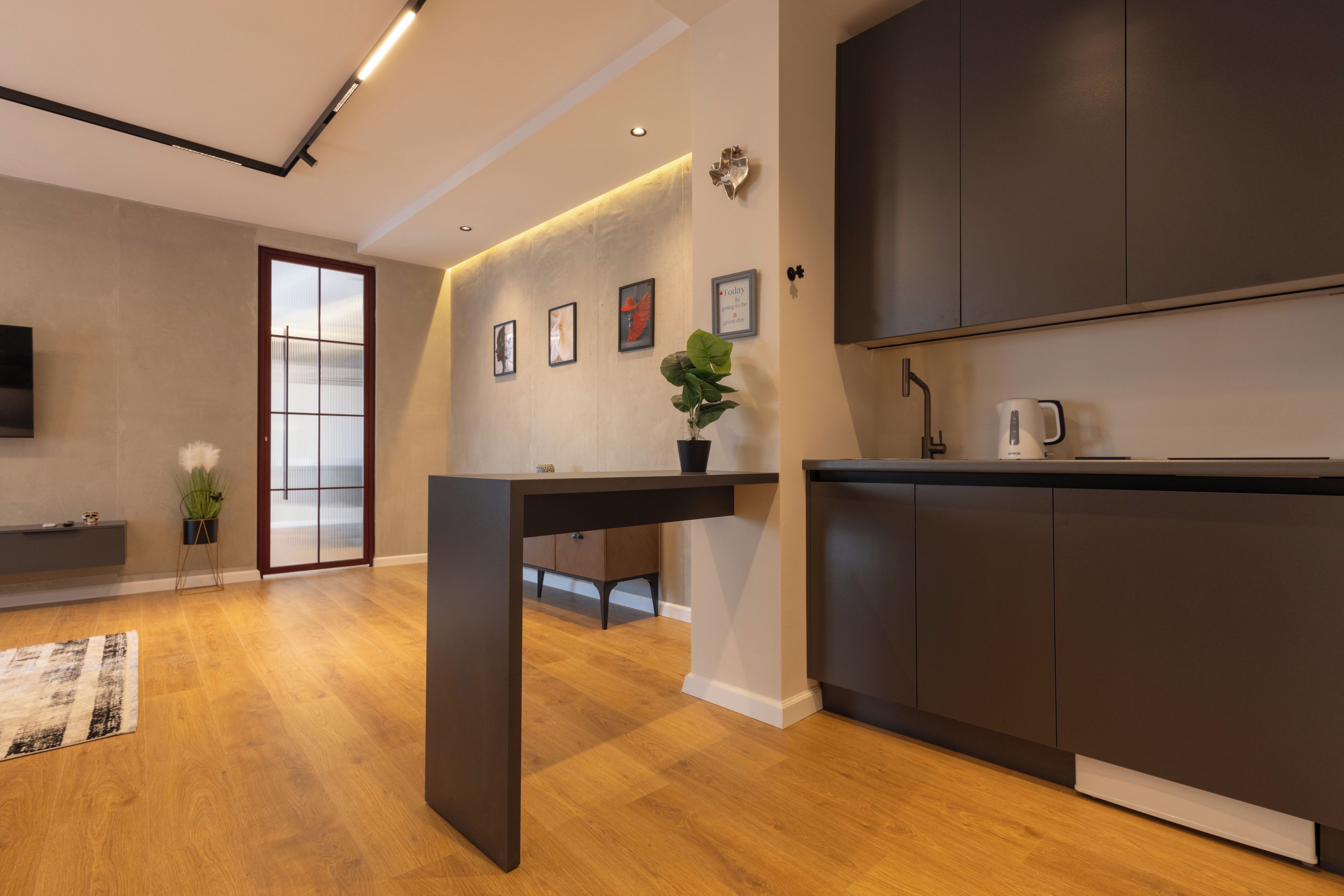 A modern kitchen with dark cabinetry, a built-in oven, and a coffee maker.