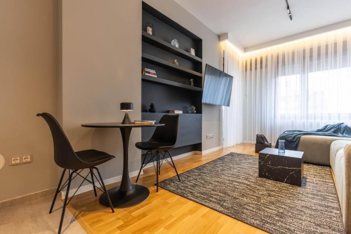 Uma sala de estar moderna com área de jantar, televisão de tela plana e um sofá.