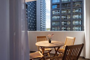 A balcony with a round wooden table, two wooden chairs, and a potted orchid. - Prishtina City Apartments 2 (Pristina)