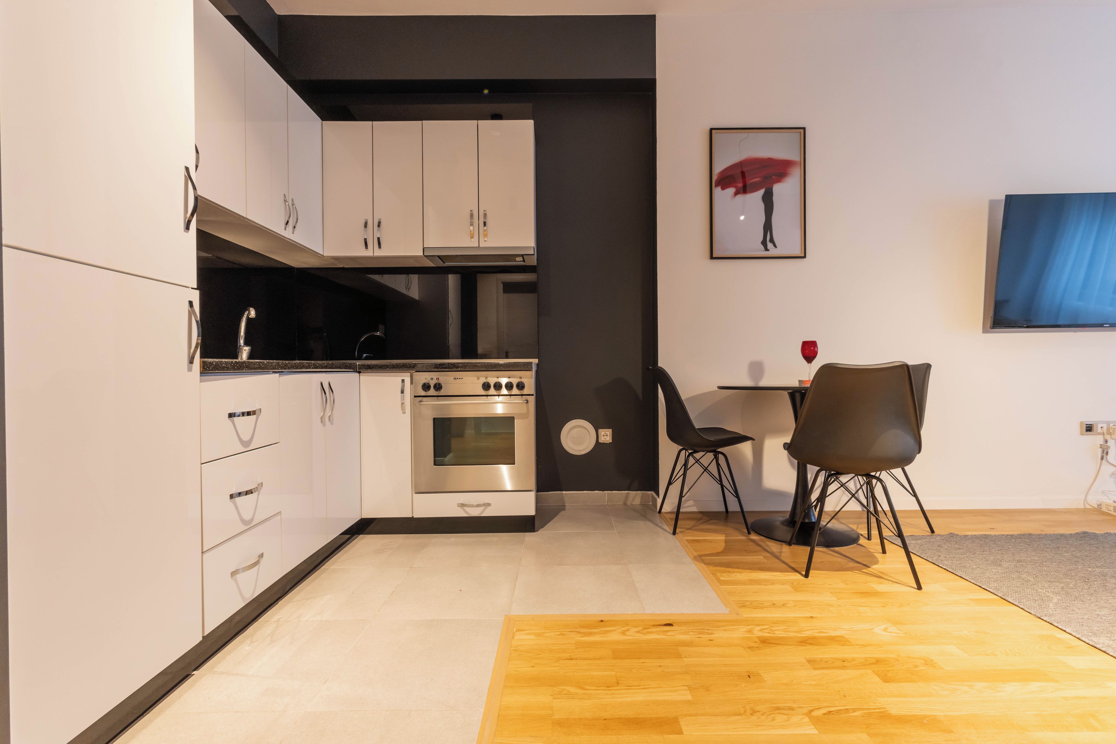 Une cuisine moderne dotée d’appareils électroménagers en acier inoxydable, de meubles blancs et d’un coin repas avec une table et des chaises.
