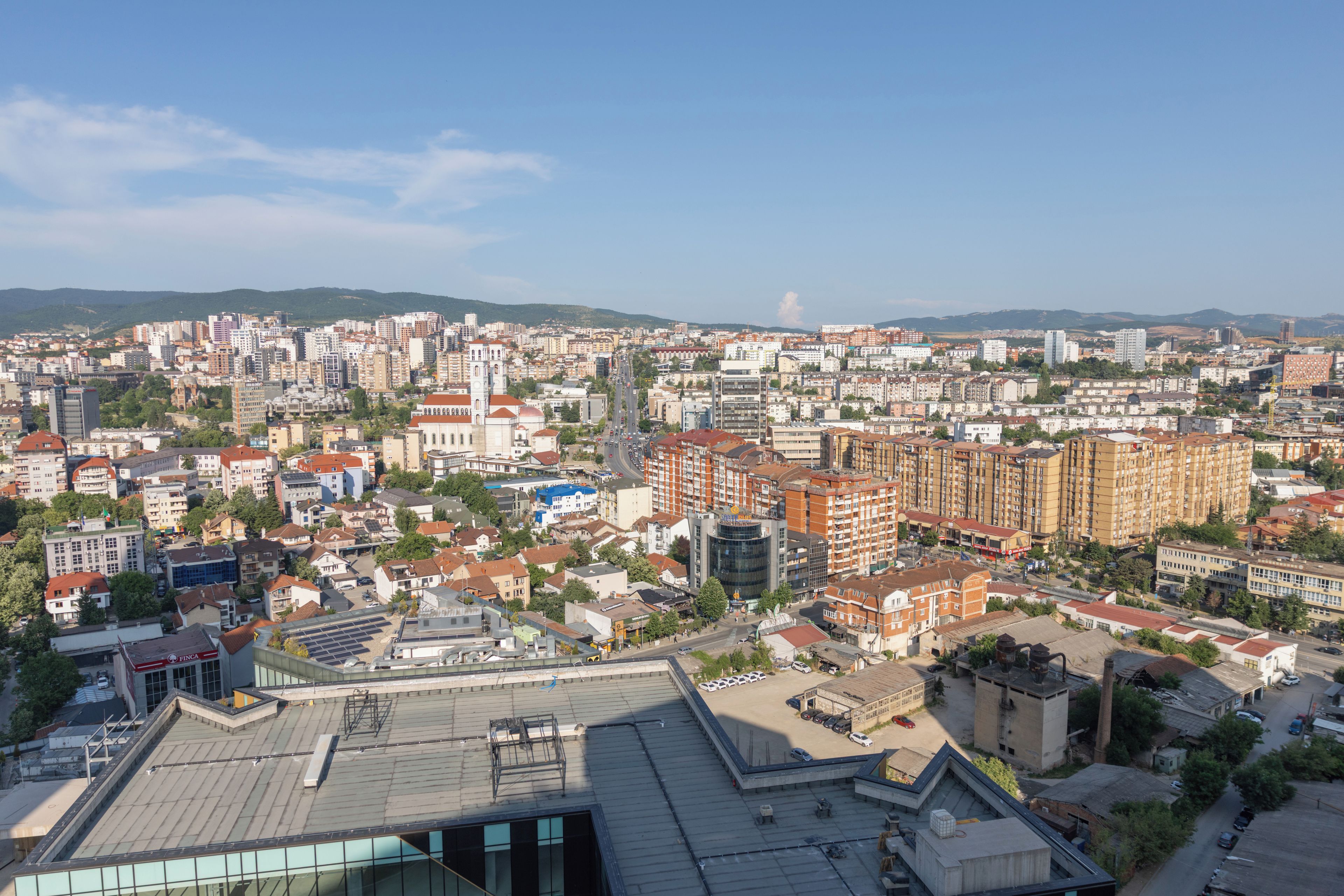 Un paisaje urbano con una mezcla de edificios residenciales y comerciales, incluyendo una iglesia destacada con un campanario.