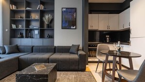 A modern living room with a sectional sofa, a marble coffee table, and a dining area with a table and chairs. - Prishtina City Apartments 2 (Pristina)