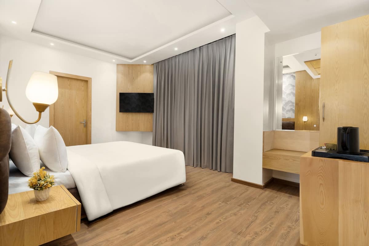 A modern hotel room with a bed, wooden furniture, a flat-screen TV, and a coffee maker.