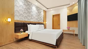 Habitación de hotel moderna con una cama grande, una mesita de noche con lámpara, cabecero de madera y una pared con estampado de árbol.