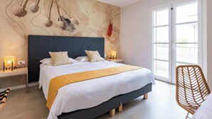 Quarto moderno com uma cama grande, mesas de cabeceira, uma cadeira e uma janela ampla.