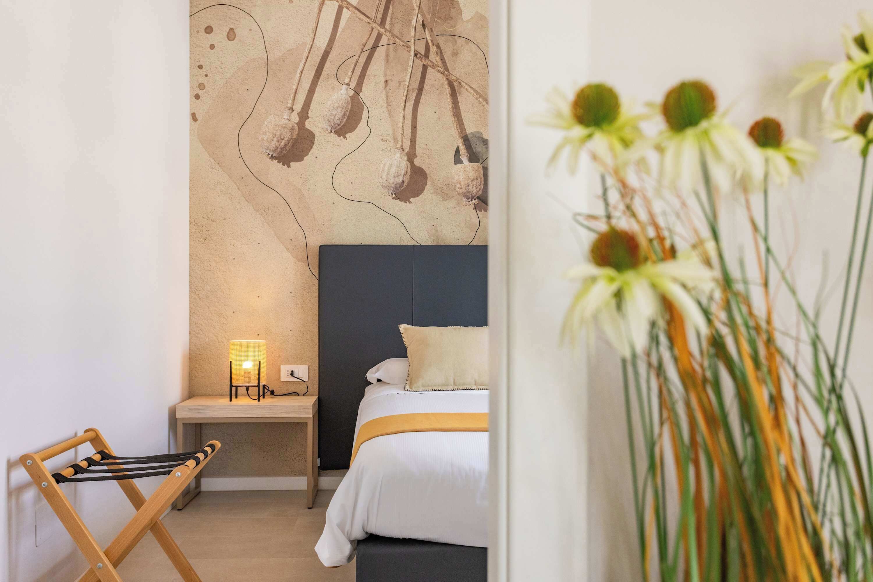 Un dormitorio con cama, mesita de noche, lámpara y una pared decorada con arte abstracto.