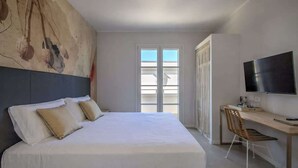 A bedroom with a bed, a desk, a chair, a TV, and a large abstract painting on the wall. - Appartamento "Isola di Panarea 2" (Carini)