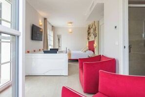 Een moderne hotelkamer met een bed, een bureau, een rode bank en een aan de muur bevestigde televisie.