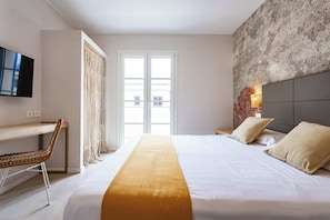 Een hotelkamer met een bed, een bureau, een stoel, een televisie en een groot raam.