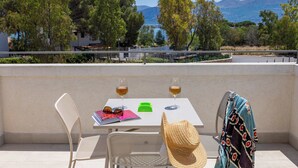 Een balkon met een tafel, twee stoelen, een hoed en twee glazen wijn.
