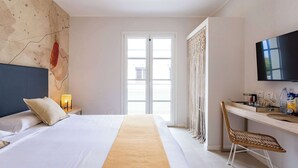 Een hotelkamer met een bed, een bureau, een televisie en een groot raam.