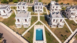 Un complex residencial amb arquitectura moderna, una piscina central i panells solars als terrats.