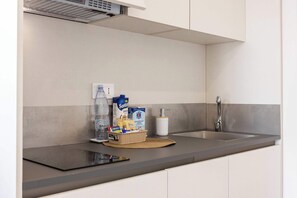 A modern kitchen with a stainless steel sink, a built-in range hood, and a woven placemat on the countertop. - Appartamento "Isola di Marettimo 1" (Carini)