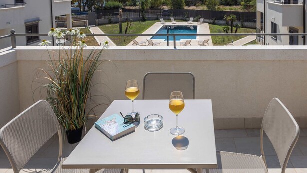 Un balcón con una mesa, dos copas de vino, un libro y una planta en maceta.