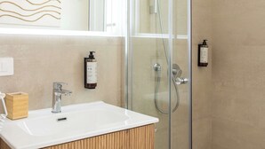 Un baño moderno con ducha envuelta en vidrio, un lavamanos blanco y muebles de madera.