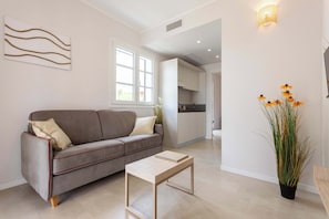 A modern living room with a sofa, a coffee table, a potted plant, and a kitchen in the background. - Appartamento "Isola di Alicudi 1" (Carini)