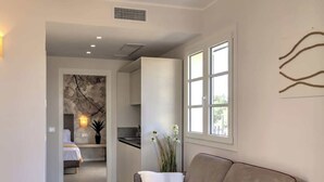 A modern living room with a sofa, a small table, and a kitchen in the background. - Appartamento "Isola di Ustica 1" (Carini)
