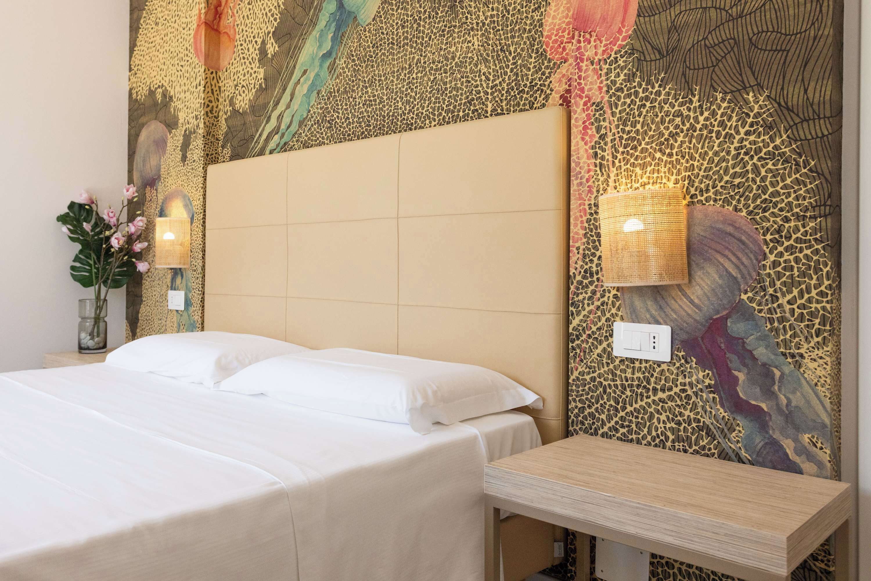Ein Hotelzimmer mit einem großen Bett, einem Nachttisch, einer Wandleuchte und einer dekorativen Wandverkleidung.