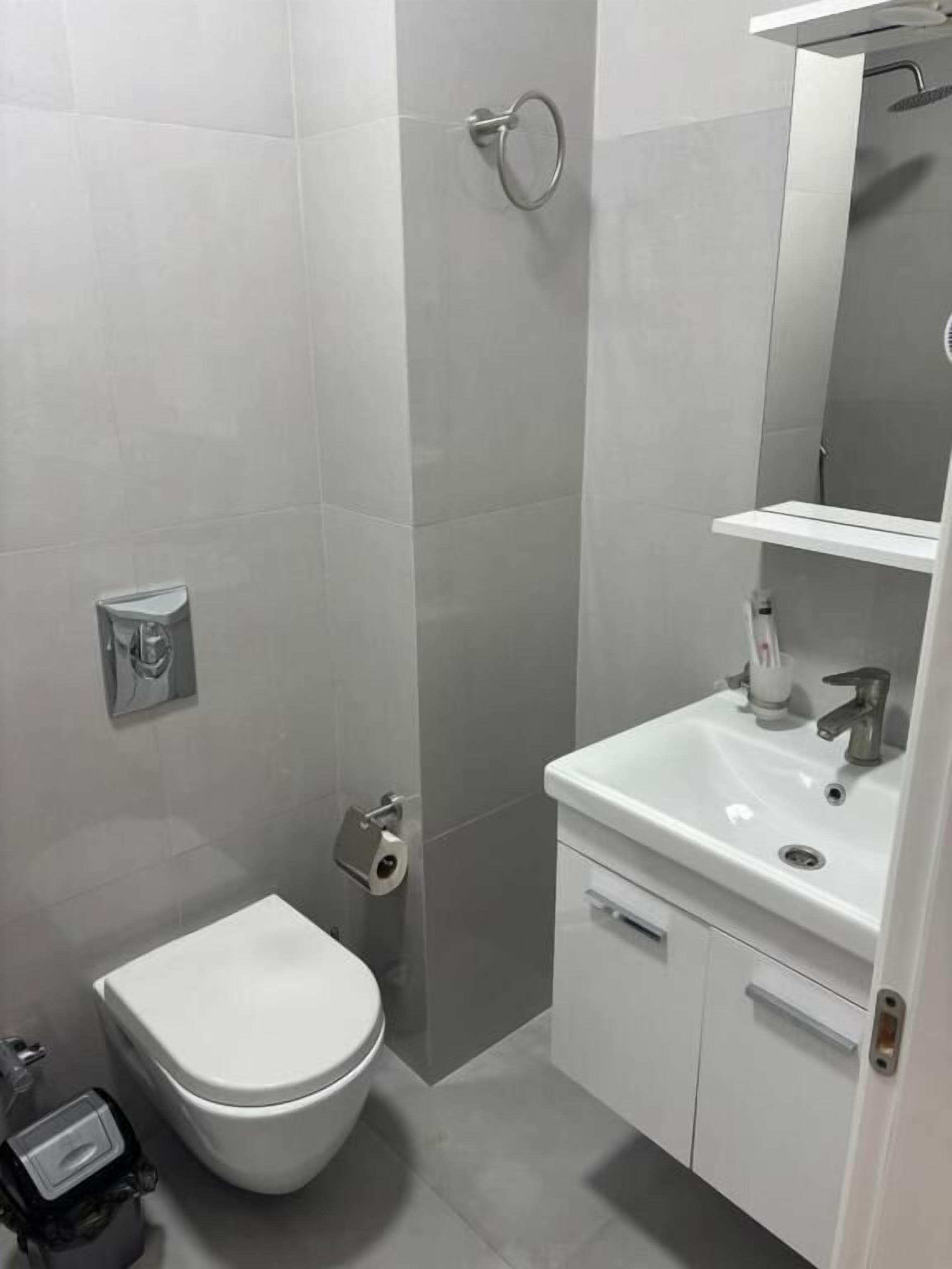 Un baño moderno con inodoro, lavamanos y ducha.