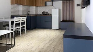 Una cocina moderna con armarios oscuros, un refrigerador blanco y un comedor con mesa y sillas.