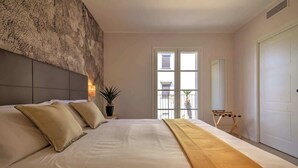 Ein Schlafzimmer mit einem großen Bett, einer Kopfteil, einer Topfpflanze, einem Fenster mit Aussicht und einer Tür.