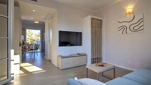 Een moderne woonkamer met een televisie, een bank en een eethoek op de achtergrond.