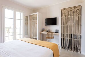 Une chambre d’hôtel équipée d’un lit, d’un bureau, d’une chaise, d’une télévision et d’une fenêtre avec des rideaux.