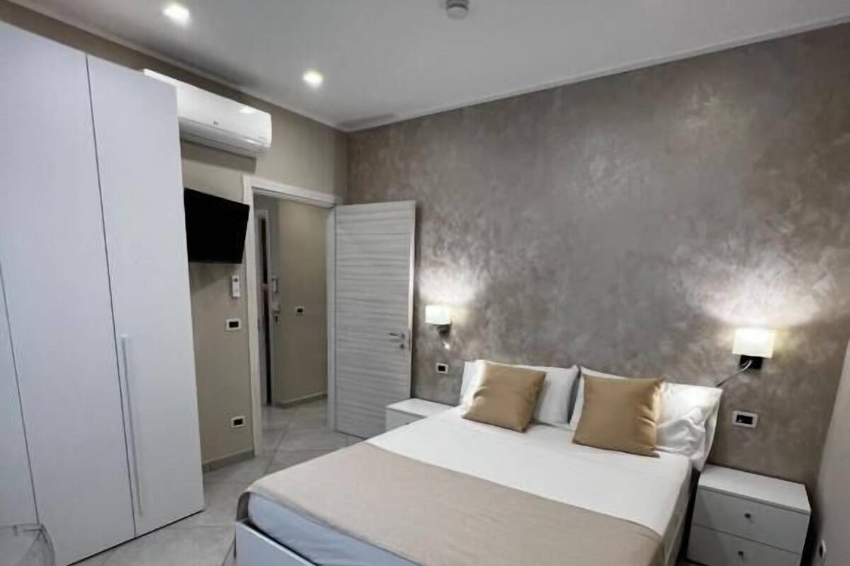 Ein modernes Schlafzimmer mit Bett, Nachttischen, einem Kleiderschrank und einer Deckenleuchte.