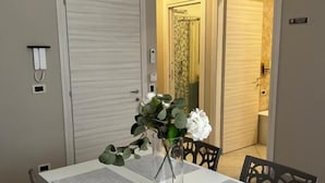 A dining area with a white table, black chairs, a vase with flowers, and a door leading to another room. - B&B Lamezia Central Airport (Lamezia Terme)