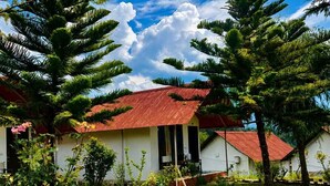 A white building with a red roof, surrounded by lush greenery and trees. - Chardham Resort Guptakashi (Ukhimath)