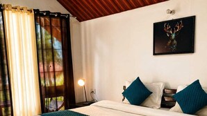 A bedroom with a bed, a nightstand, a lamp, a framed artwork, and a window with curtains. - Chardham Resort Guptakashi (Ukhimath)