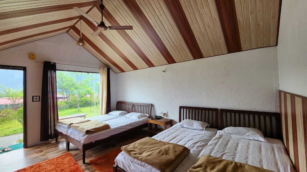 A bedroom with two beds, a ceiling fan, and a view of greenery outside.