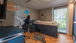 A bedroom with a bed, desk, chair, and a window with blinds. - De Wiedense Meren - Villa Waterrijk MIVA | 3p (Wanneperveen)