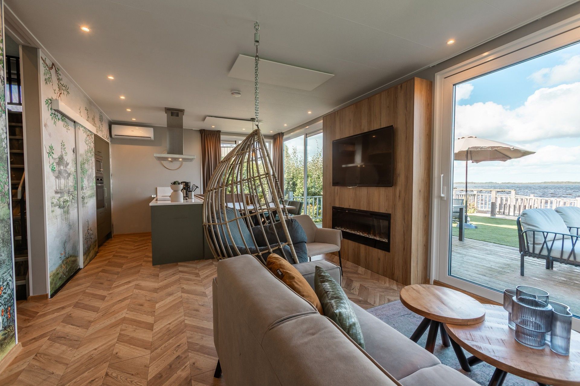 Una sala moderna con sofá, comedor, televisor y vistas al exterior.