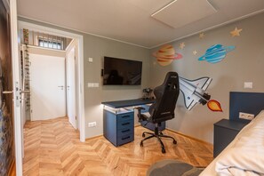 A room with a desk, chair, and a wall with space-themed decorations.