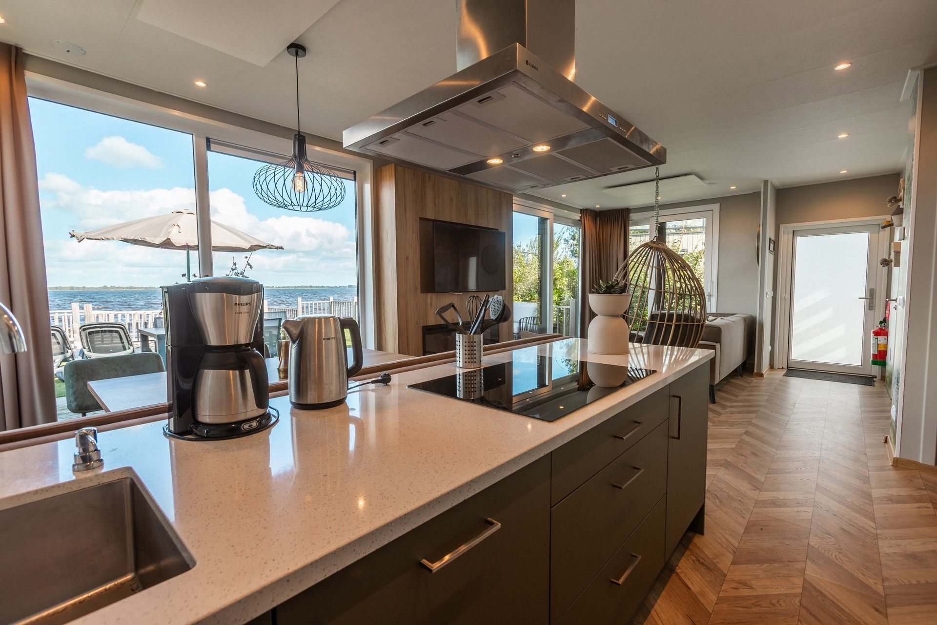 A modern kitchen with a large island, stainless steel appliances, and a view of the sea.
